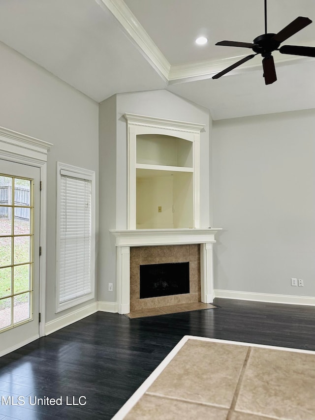 unfurnished living room featuring a tiled fireplace, ceiling fan, dark hardwood / wood-style floors, and crown molding