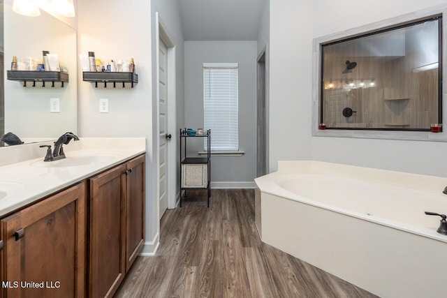 bathroom with wood-type flooring, a bath, and vanity