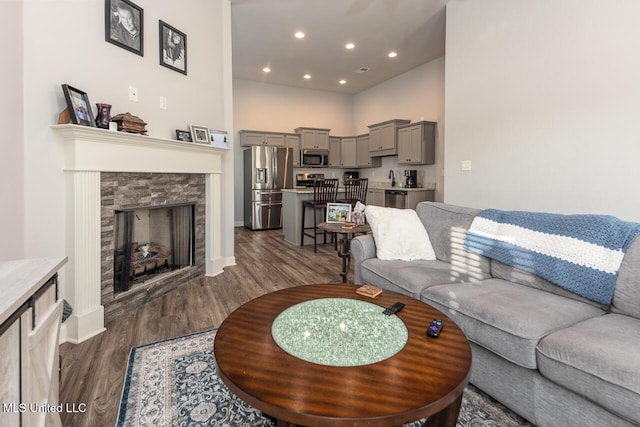 living room featuring dark wood-type flooring, a fireplace, and a towering ceiling