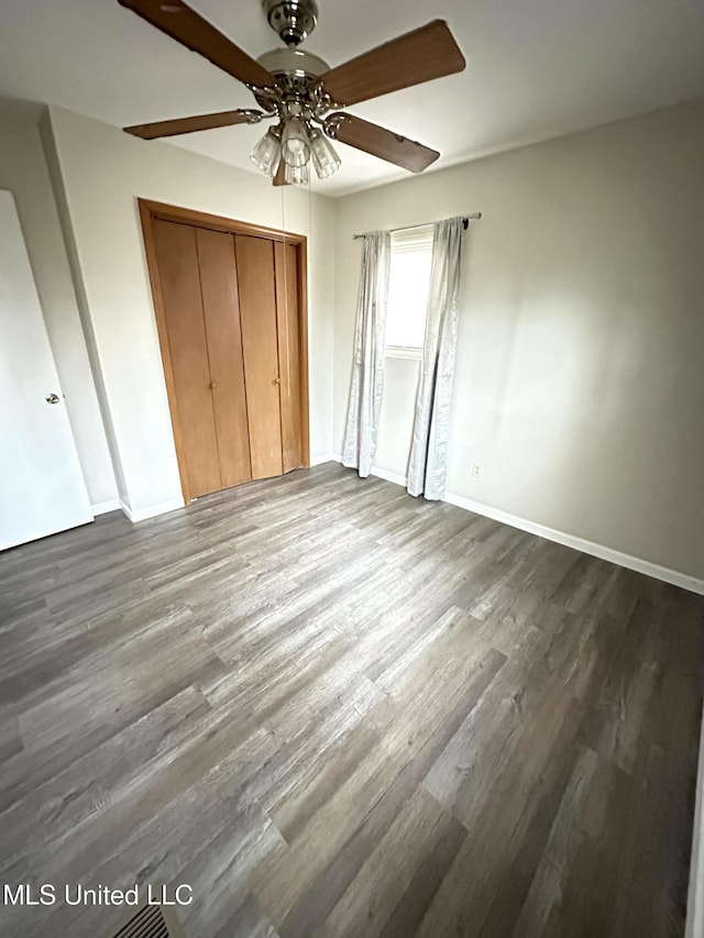52 Dog Wood Cove Rd, Coffeeville, MS 38922 - unfurnished bedroom featuring ceiling fan, dark wood-type flooring, a closet, and baseboards