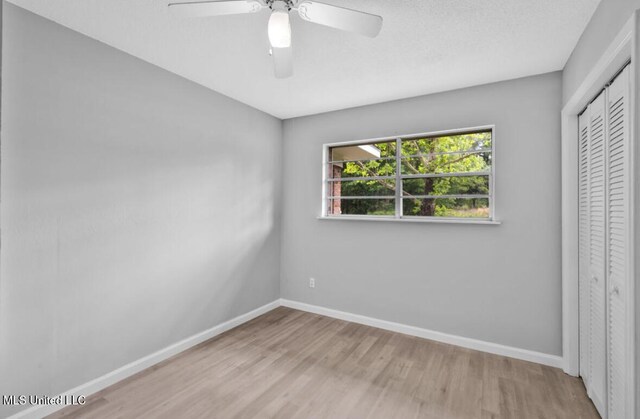 unfurnished bedroom with wood finished floors, baseboards, a ceiling fan, and a closet