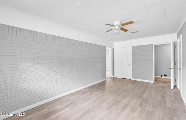 unfurnished bedroom with visible vents, a closet, baseboards, brick wall, and wood finished floors