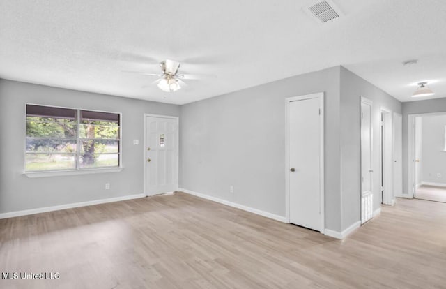 spare room featuring a ceiling fan, visible vents, light wood-style flooring, and baseboards