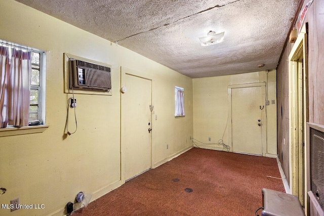 basement featuring carpet flooring, an AC wall unit, and a textured ceiling