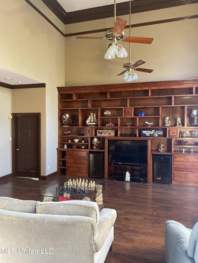 living room with crown molding, ceiling fan, a high ceiling, and dark hardwood / wood-style flooring