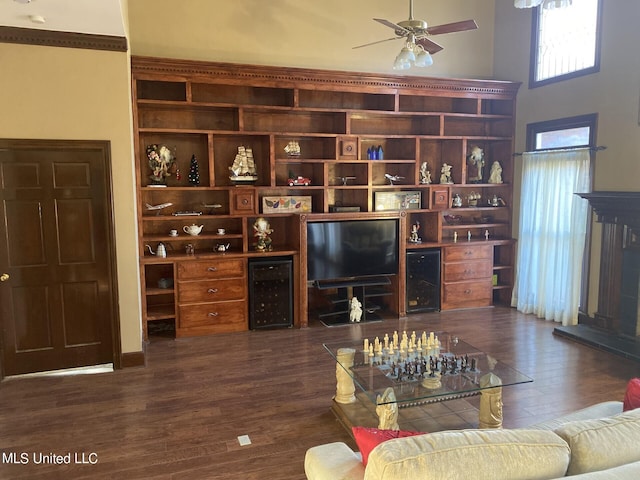 living room with dark wood-type flooring, ceiling fan, and a high ceiling