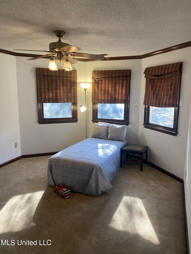 bedroom featuring ceiling fan, a textured ceiling, carpet floors, and ornamental molding