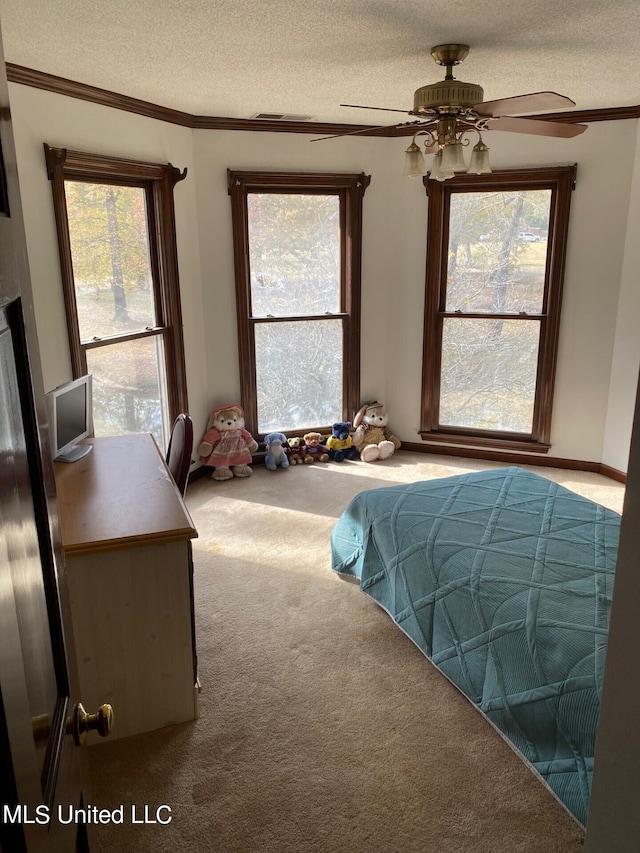 carpeted bedroom with ornamental molding, a textured ceiling, multiple windows, and ceiling fan