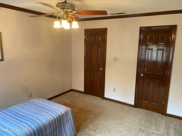 carpeted bedroom with ceiling fan, a textured ceiling, and ornamental molding