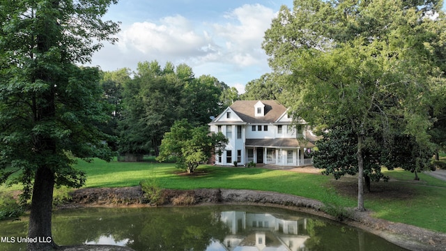 back of house featuring a water view and a lawn