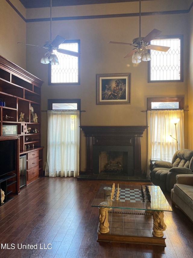 living room featuring ceiling fan, a towering ceiling, and dark hardwood / wood-style floors