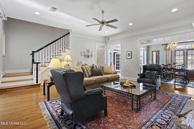 living room featuring crown molding, hardwood / wood-style floors, and ceiling fan with notable chandelier