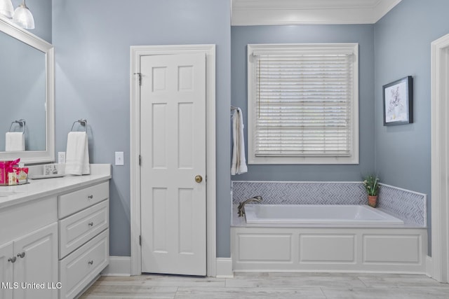 bathroom with a washtub, vanity, and ornamental molding