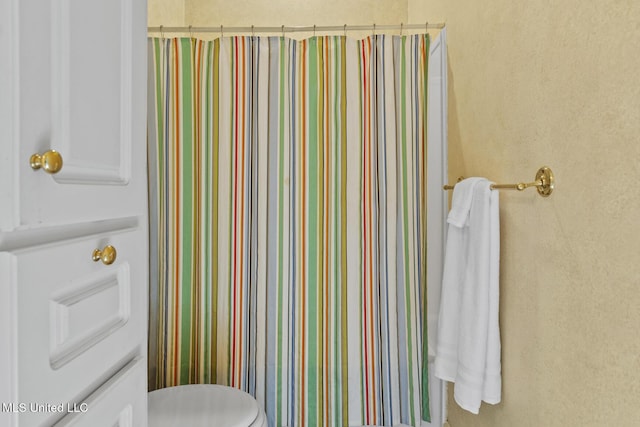 bathroom with toilet and curtained shower