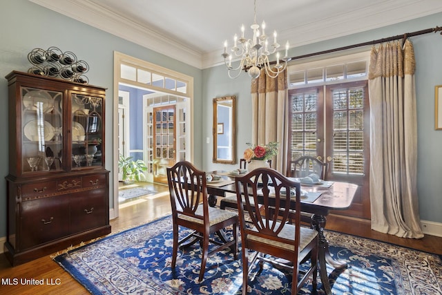 dining area featuring crown molding, hardwood / wood-style floors, french doors, and a notable chandelier