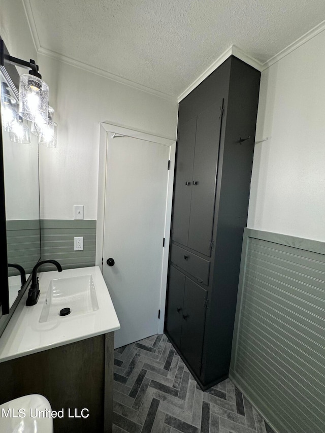 bathroom featuring vanity, toilet, a textured ceiling, and ornamental molding