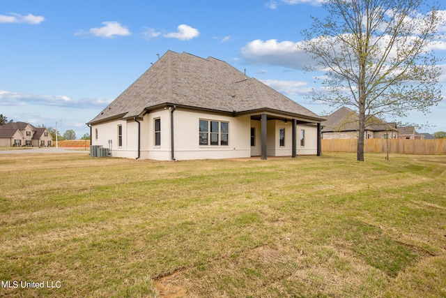 rear view of property featuring a yard and central AC unit