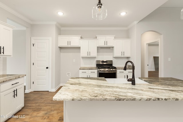 kitchen with white cabinetry, stainless steel gas range oven, hardwood / wood-style flooring, and tasteful backsplash