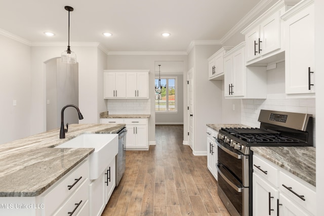 kitchen with white cabinetry, stainless steel appliances, light wood-type flooring, and pendant lighting