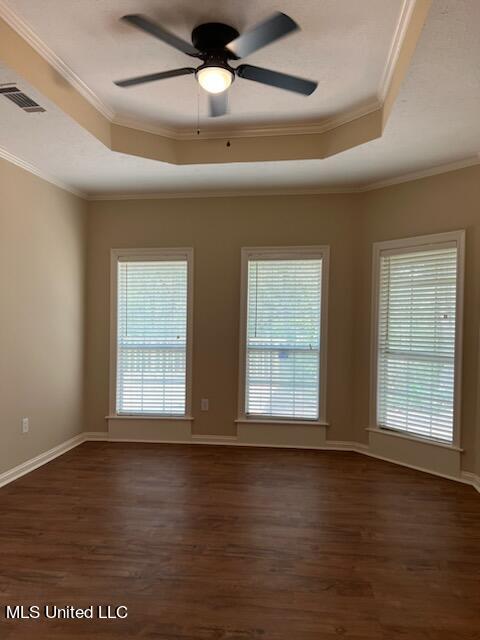 unfurnished room featuring ornamental molding, dark wood-type flooring, a tray ceiling, and ceiling fan