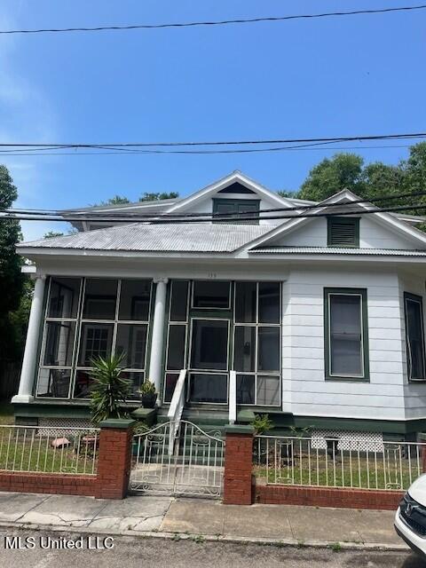 139 Fayard St, Biloxi, MS 39530 - view of front of house featuring a fenced front yard, a sunroom, and metal roof