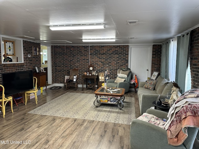 living room featuring hardwood / wood-style flooring and brick wall