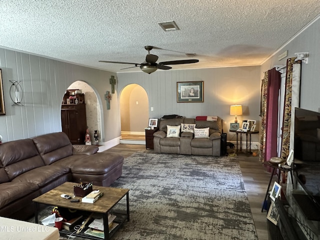 living room featuring ornamental molding, a textured ceiling, ceiling fan, and dark wood-type flooring