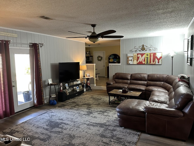 living room with wood walls, hardwood / wood-style floors, and ceiling fan