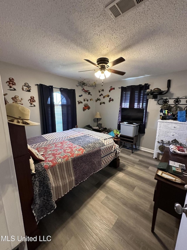 bedroom with hardwood / wood-style flooring, ceiling fan, and a textured ceiling