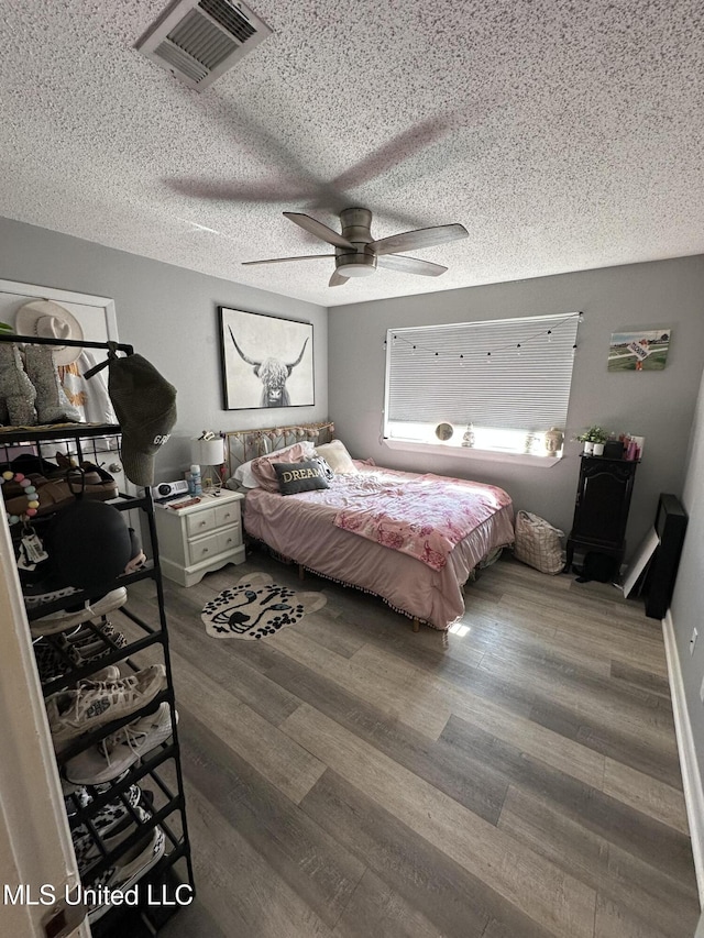 bedroom with hardwood / wood-style floors, a textured ceiling, and ceiling fan