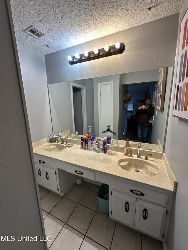 bathroom with tile patterned flooring, vanity, and a textured ceiling