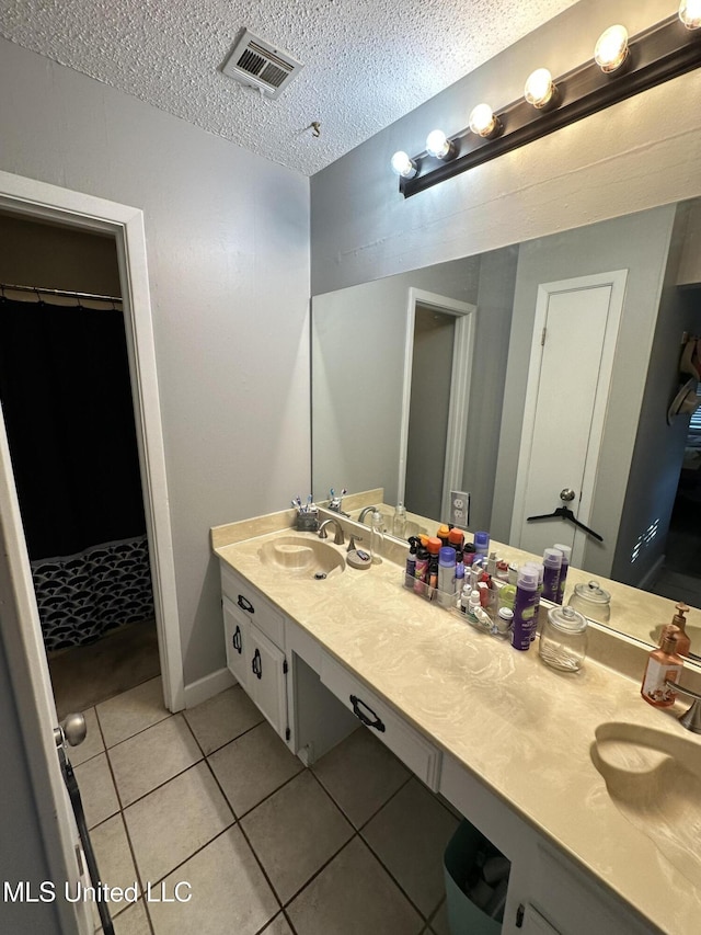 bathroom with tile patterned flooring, vanity, and a textured ceiling