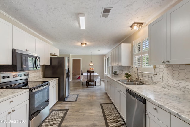 3590 Shady Oaks Dr, Olive Branch, MS 38654 - kitchen featuring appliances with stainless steel finishes, a sink, a textured ceiling, backsplash, and light wood-style flooring