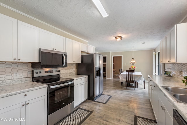 3590 Shady Oaks Dr, Olive Branch, MS 38654 - kitchen featuring stainless steel appliances, white cabinets, a textured ceiling, decorative backsplash, and light wood-style floors
