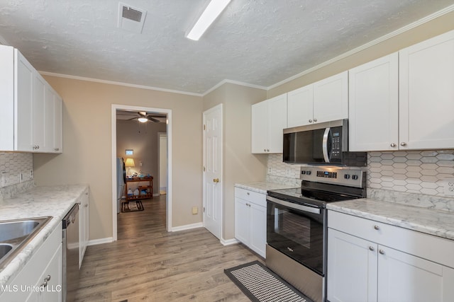 3590 Shady Oaks Dr, Olive Branch, MS 38654 - kitchen featuring stainless steel appliances, light wood finished floors, white cabinets, tasteful backsplash, and a textured ceiling