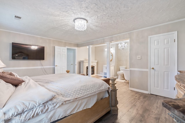 3590 Shady Oaks Dr, Olive Branch, MS 38654 - bedroom featuring wood-type flooring, decorative columns, a textured ceiling, ensuite bath, and a fireplace
