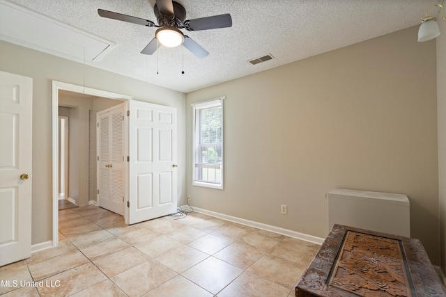 3590 Shady Oaks Dr, Olive Branch, MS 38654 - unfurnished bedroom featuring attic access, light tile patterned floors, a textured ceiling, baseboards, and a ceiling fan