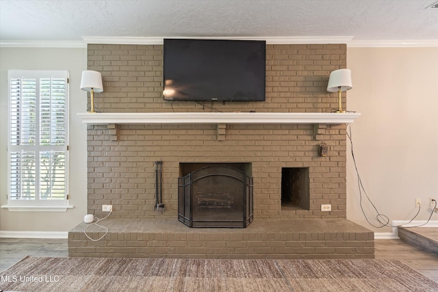 3590 Shady Oaks Dr, Olive Branch, MS 38654 - detailed view of a brick fireplace, wood finished floors, a textured ceiling, baseboards, and crown molding