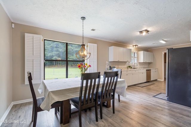 3590 Shady Oaks Dr, Olive Branch, MS 38654 - dining area featuring a chandelier, light wood-style floors, a textured ceiling, baseboards, and crown molding