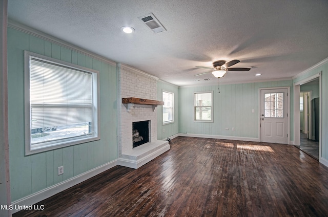 unfurnished living room with a textured ceiling, a wealth of natural light, a brick fireplace, and dark hardwood / wood-style flooring