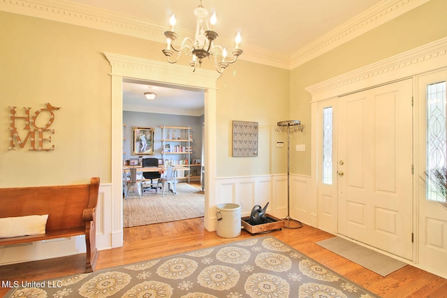 entrance foyer featuring hardwood / wood-style flooring, ornamental molding, and a notable chandelier