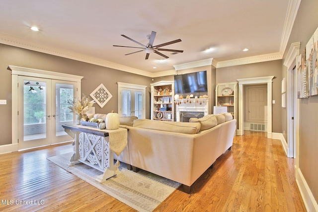 living room featuring ceiling fan, light hardwood / wood-style floors, ornamental molding, and french doors