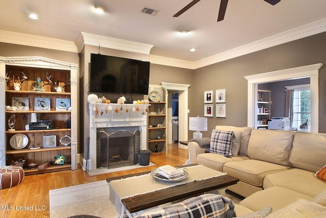 living room with light wood-type flooring, ceiling fan, and ornamental molding