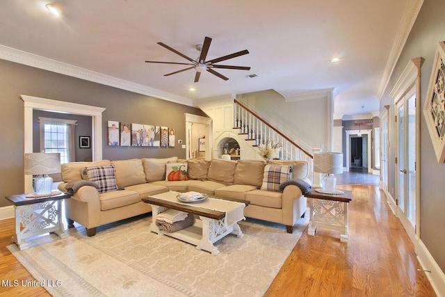 living room with light hardwood / wood-style floors, ceiling fan, and ornamental molding