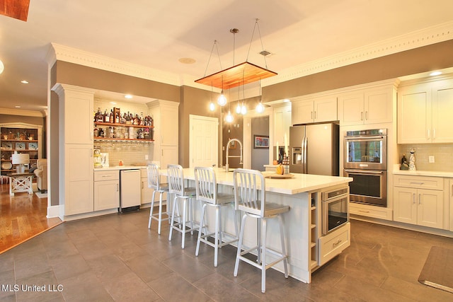 kitchen with backsplash, a kitchen island with sink, a breakfast bar area, decorative light fixtures, and stainless steel appliances