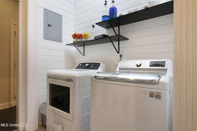 laundry room featuring wood walls, electric panel, and washing machine and clothes dryer