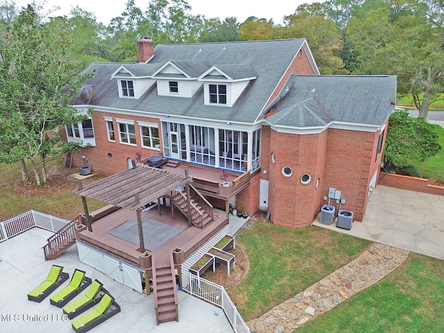 rear view of property featuring a sunroom, a deck, cooling unit, and a lawn