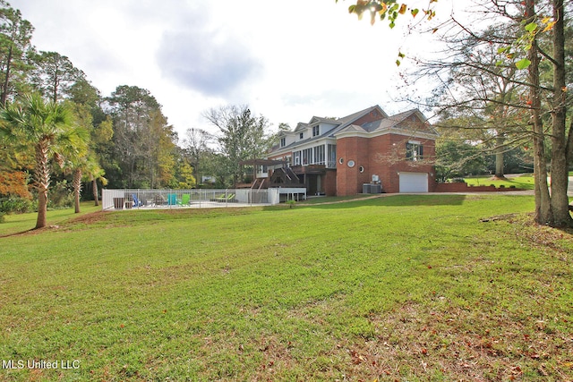 view of yard with a garage, a wooden deck, and central AC