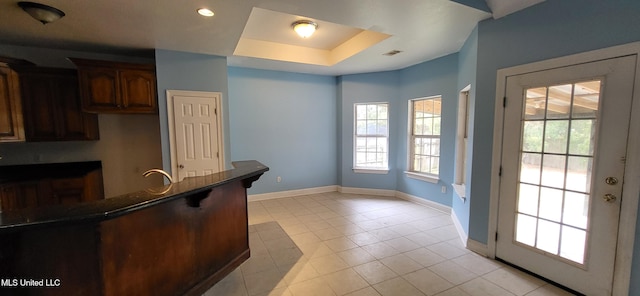 kitchen featuring sink, light tile patterned flooring, and a tray ceiling