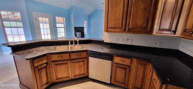 kitchen with kitchen peninsula, dishwashing machine, sink, light tile patterned floors, and dark stone countertops